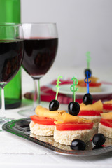 delicious canapes on iron dressing on a white wooden background near the wineglasses with wine