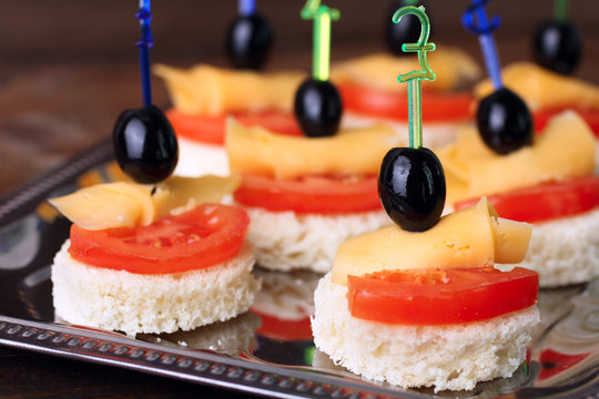 delicious canapes on iron spacing on brown wooden background