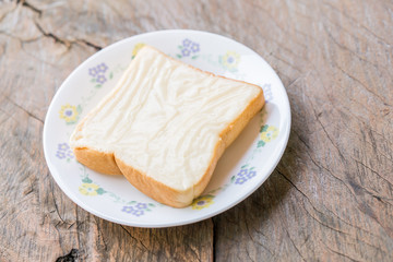 milk flavored cream spread bread slices in dish on wooden table
