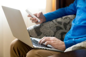 Young man using laptop and phone