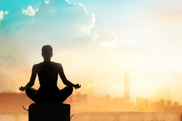Abstract woman meditating on colorful city in the sunset