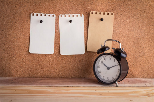 note papers on cork board with alarm clock