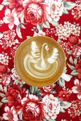 cup of latte art coffee on background texture fabric floral pattern.