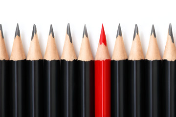 Red pencil standing out from crowd of plenty identical black pencils on white background....