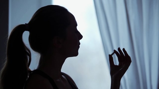 Young woman deliberates whether to take a pill