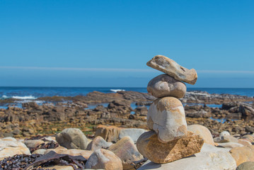 Fototapeta na wymiar Stacked rocks by the ocean side and horizon in the background