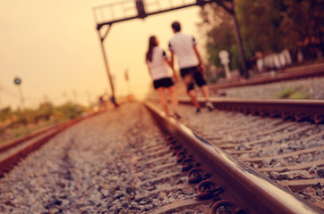 Image for background, blrred couple walking on the railroad, retro filter.