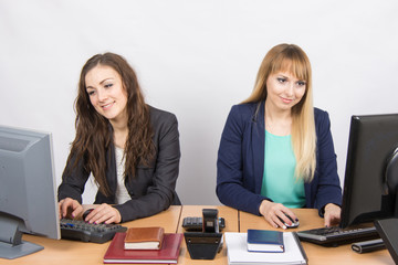 Two young girls working at the computer sitting at a table in the office