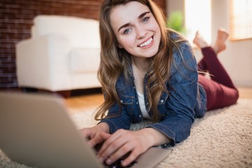 Fototapeta premium Pretty woman lying on the couch using laptop