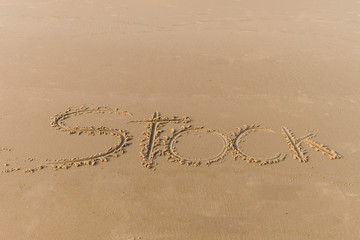 Word stock writing in sand, on sunset beach