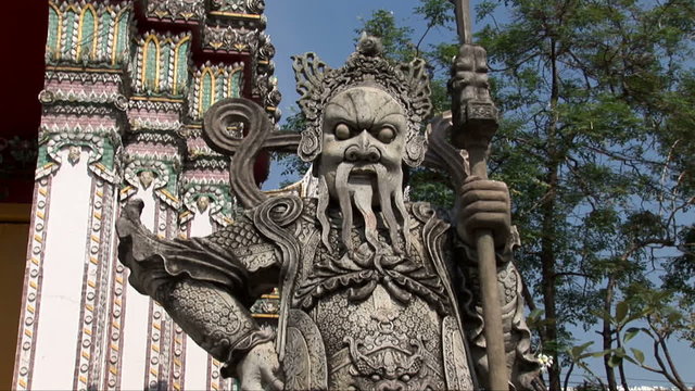 Tilt up a stone warrior at Wat Po Temple in Thailand