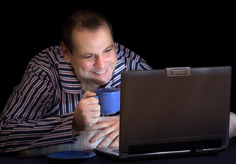 happy man with computer in bed