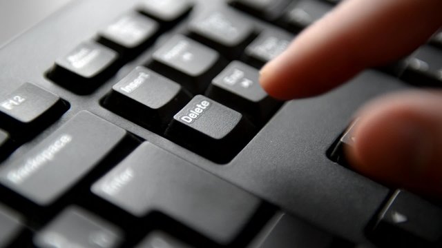 The man thinks and hesitates before press the key Delete, view of computer keyboard, finger.