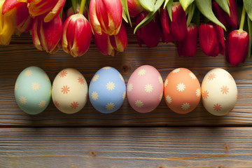 Easter eggs and colorful flowers on wooden background