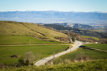 Green hills, road and snowy mountain peaks