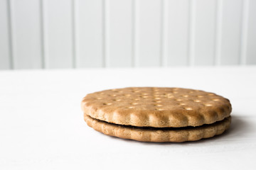 Single biscuit on a white wooden base and white wooden background