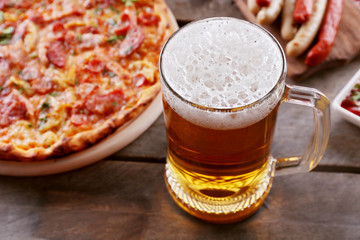 Grilled sausages, delicious pizza and glass of beer on wooden table, close up