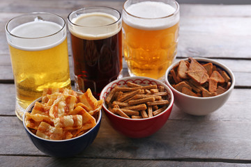Various types of beer and snacks on wooden table