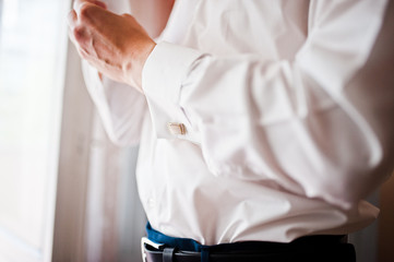 Fototapeta premium A young man wearing a cuff link, groom preparing for the wedding