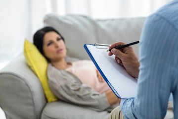 Doctor writing on clipboard while consulting pregnant woman