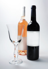 Red wine bottle and rose wine bottle with blank labels and elegant wine glass, studio shot