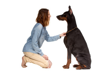 Girl sitting on her knees in front of a large black dog