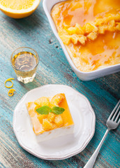 Cheesecake, cottage cheese pudding with fresh oranges and orange marmalade, jam glaze on a white plate on a turquoise wooden background