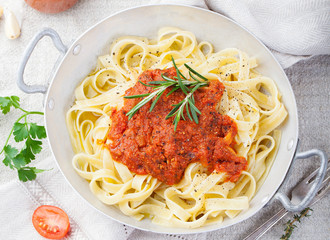 Tagliatelle pasta with tomato sauce and red pesto Top view