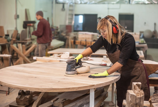 Female carpenter Using Electric Sander for wood