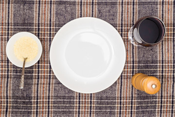 Empty white plate with glass of wine and bowl of parmesan. View from above.