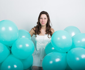 Fototapeta na wymiar beautiful curly girl in a white dress and sunglasses in the style of disco playing with balloons