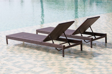 Fototapeta na wymiar Swimming pool and two deck chairs, close up
