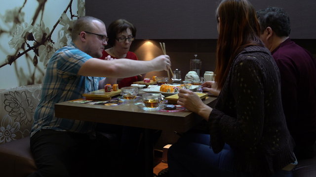 Friends eat sushi and rolls at Japanese restaurant