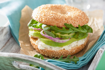 avocado sandwich on bagel with cream cheese onion cucumber arugu