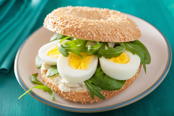 breakfast sandwich on bagel with egg cream cheese arugula