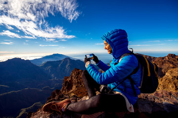 Woman in blue jacket and backpack traveling mountains near Andenes viewpoint on La Palma's island highest point in Spain