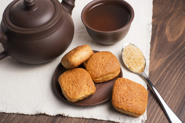 Square mug of tea with shortbread biscuits, on a brown table and a napkin