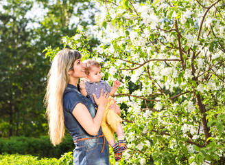 Happy woman and child in the blooming spring garden.  Mothers day holiday concept