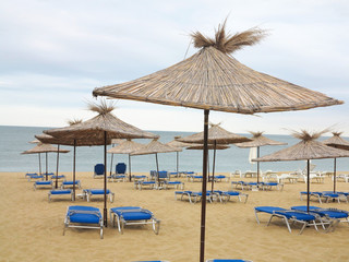Beach chairs and umbrella on the sand near sea, blue sky