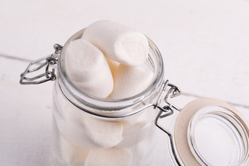 Marshmallows in a glass jar on wooden table.