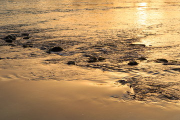 Rocks in a river with the sunlight reflected in the flowing water.