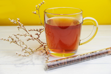 Tea in glass cup with coffee beans on yellow background