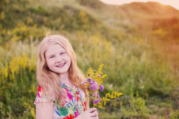Naklejka na ściany i meble happy blond girl on meadow at sunset