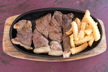 Grilled beef on a hot dish with french fries