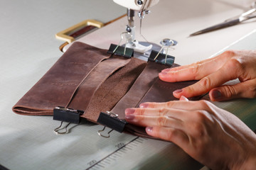 Woman's hands making leather accessory