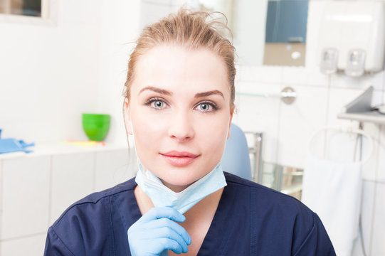 Smiling woman dentist in close-up holding dental mask