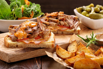 Sandwich with shredded pork, roasted potatoes and salad