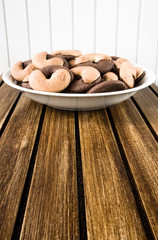 A dish full of cookies on brown wooden base and white wooden background