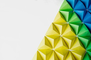 Origami 3 dimension shapes in green, blue and yellow colors with free copy space on the left side. Great for using in web.