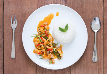 Red pork curry (Panang) with rice in white plate on wooden backg